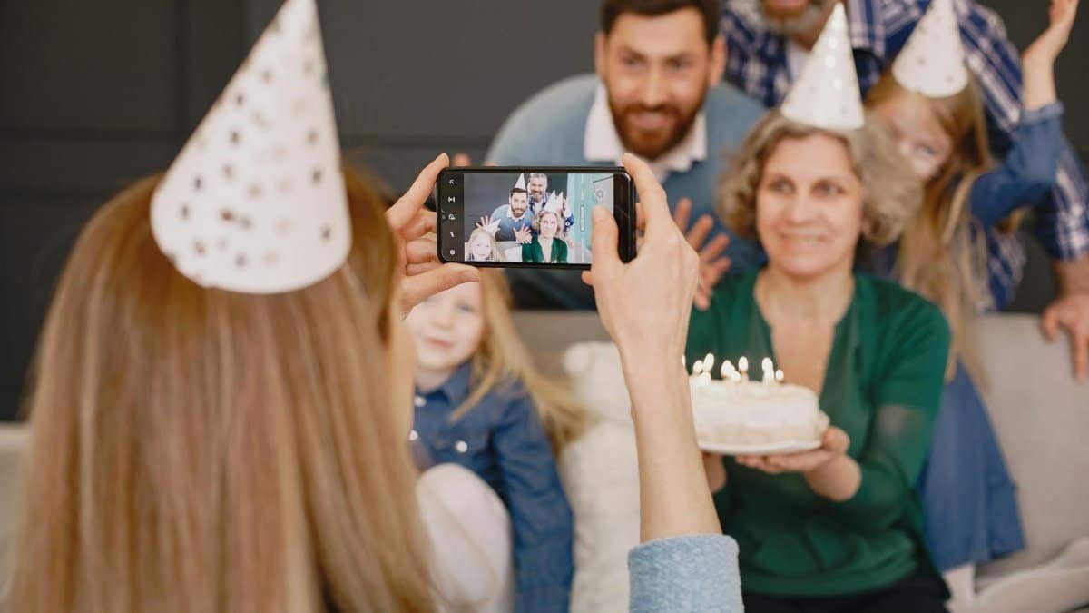 Family gathering celebrating with cake, party hats, and smiles, captured in a cozy setting.