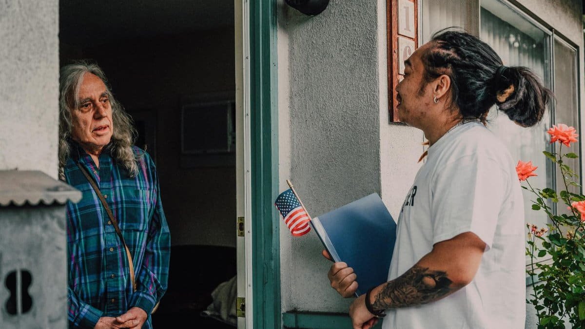 A volunteer engages with a resident during a door-to-door campaign, fostering community interaction.