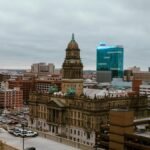 Aerial view of Detroit city showcasing historic and modern buildings under a cloudy sky.