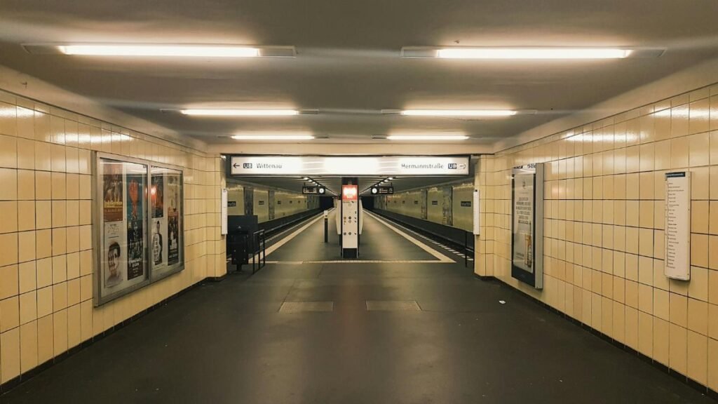 Deserted hallway of a Berlin subway station with yellow tiles and bright lighting.