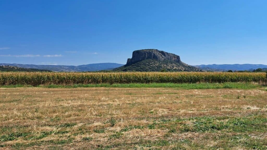 A beautiful mesa in the middle of a vast open field with clear blue skies.