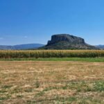 A beautiful mesa in the middle of a vast open field with clear blue skies.