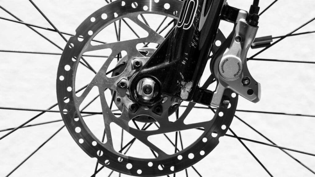Detailed black and white image of a bicycle wheel highlighting disc brakes and spokes.