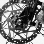 Detailed black and white image of a bicycle wheel highlighting disc brakes and spokes.
