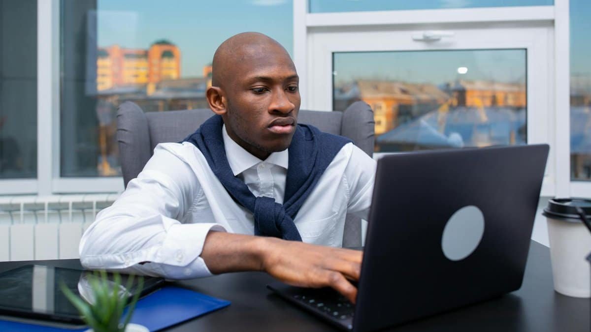Focused businessman working on a laptop in a modern office setting, conveying professionalism and productivity.