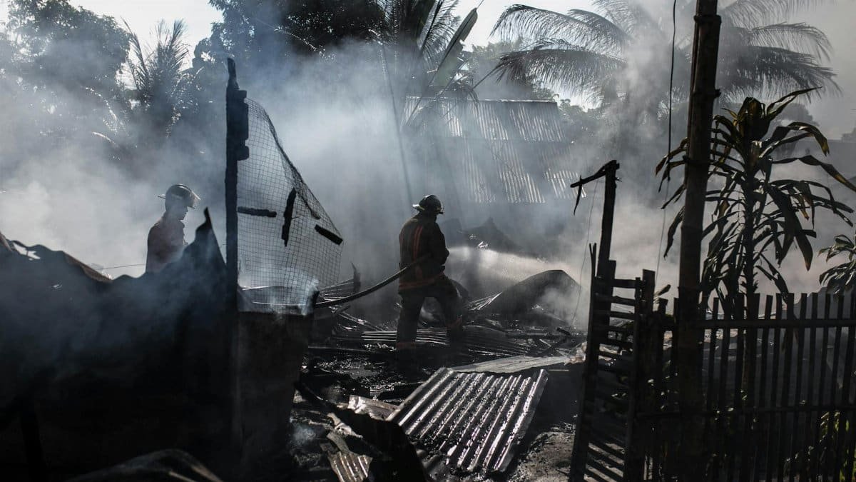 Brave firefighters battle a blaze amidst thick smoke in an outdoor setting.
