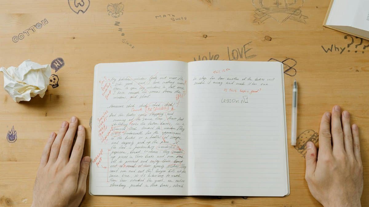 Close-up of a notebook with handwritten notes and drawings on a wooden desk.