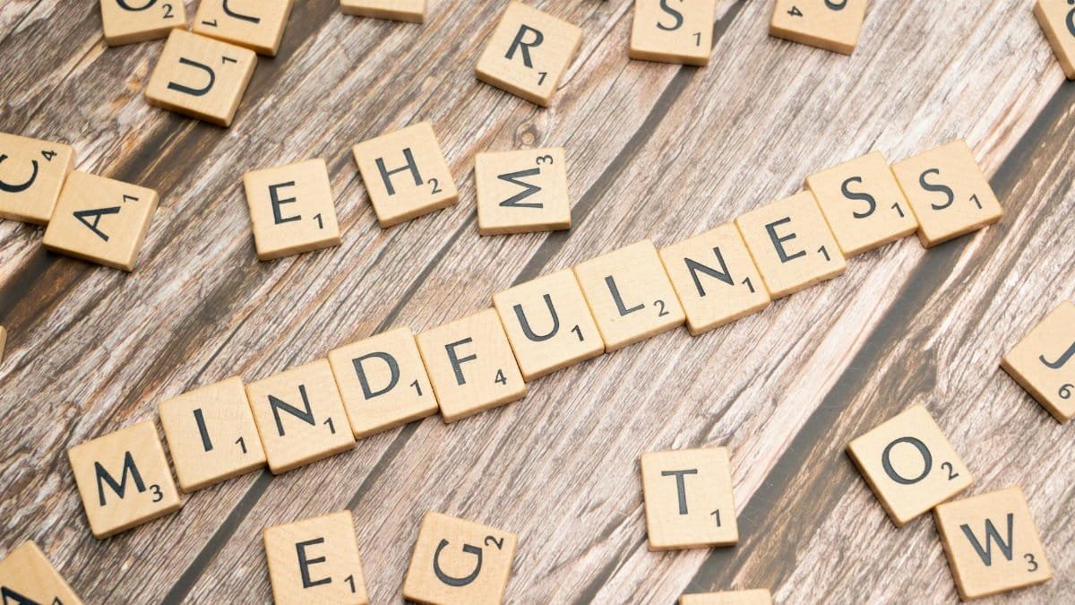 Wooden letter tiles spelling 'mindfulness' on a rustic wood background.