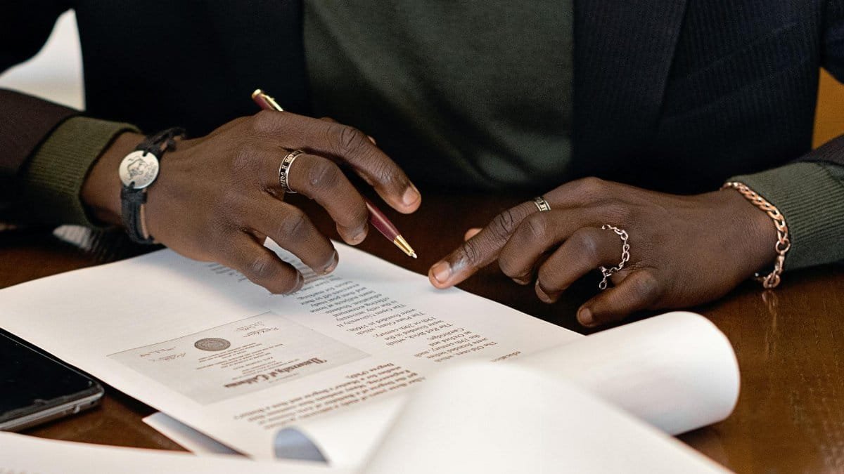 A business professional's hands signing a document at a desk, focusing on details.