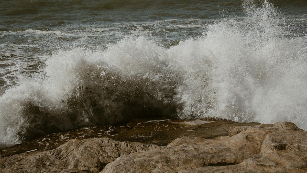 Dramatic capture of ocean waves crashing against a rocky shoreline, showcasing nature's raw power.