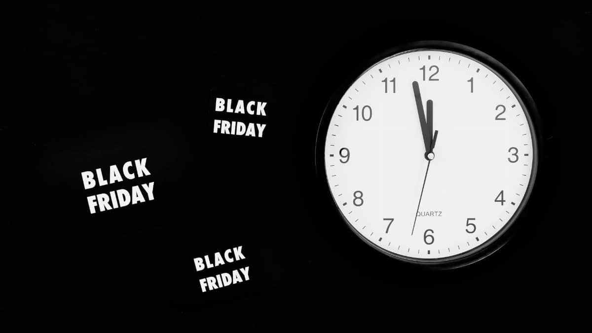 Analogue clock striking midnight for Black Friday sales on a black background.