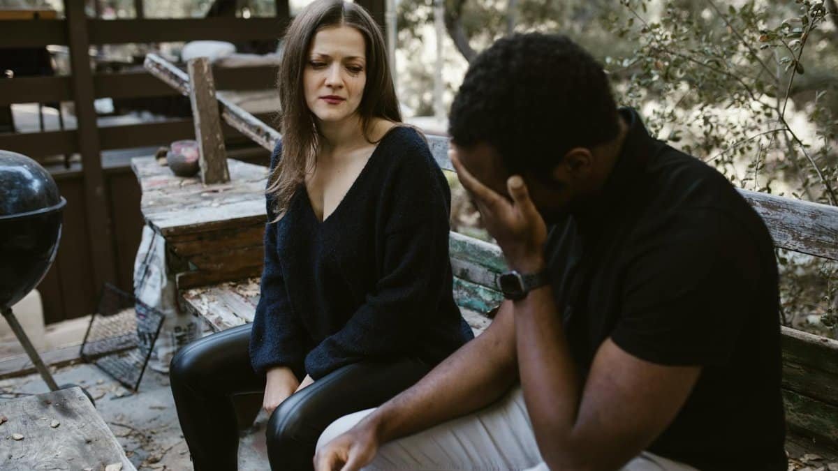 A couple having an emotional conversation outdoors, conveying sadness and concern.