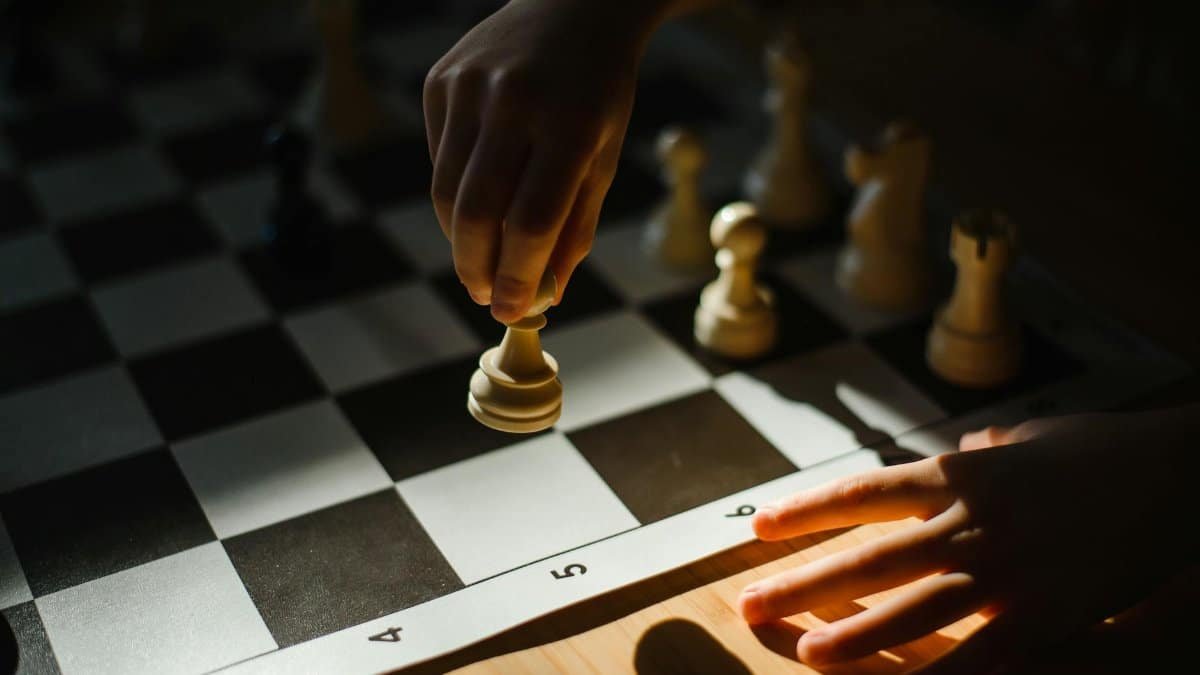 Close-up of a child's hand making a strategic chess move on a chessboard.