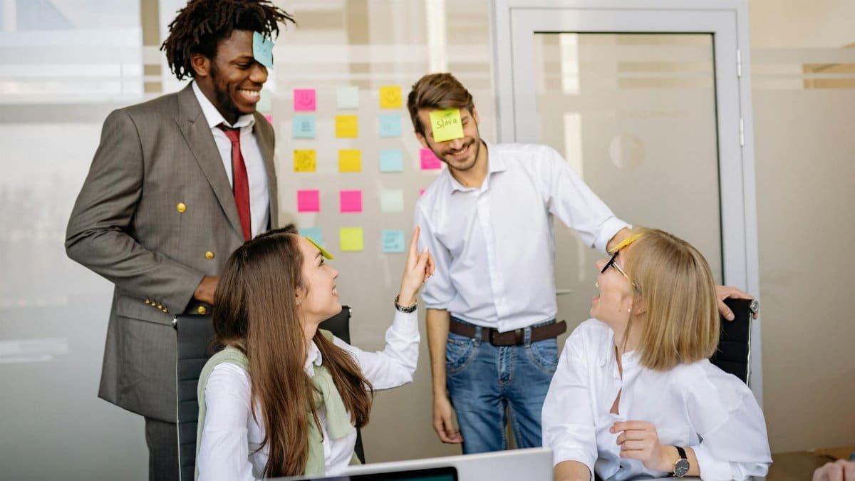 A diverse team engages in a fun brainstorming session with sticky notes and laughter.