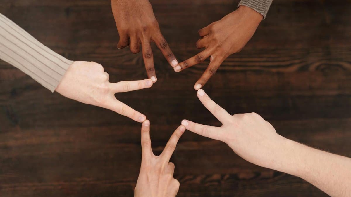 Diverse hands forming a star shape, symbolizing unity and teamwork indoors.