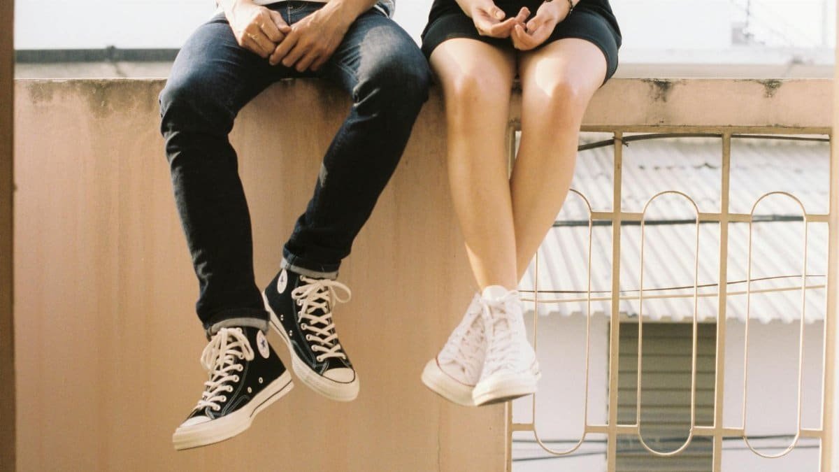 A relaxed couple sitting on a ledge, wearing stylish sneakers, showcasing togetherness.
