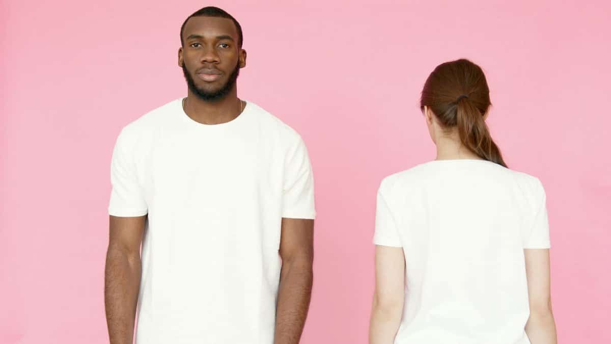 Two models showcasing white t-shirts on a pink background, front and back views.