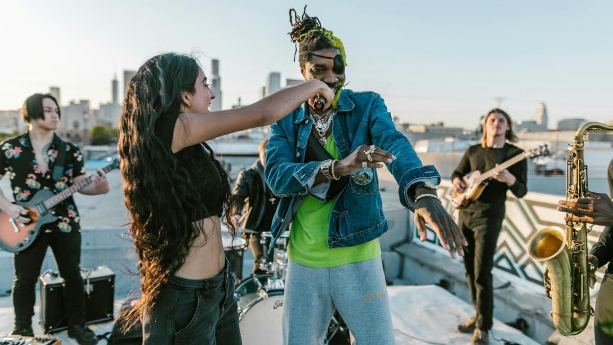 Energetic outdoor music performance with band, singers, and instruments on rooftop.
