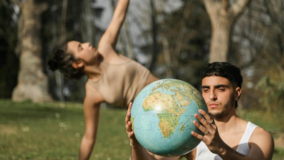 Two young adults engage with a globe outdoors, symbolizing global awareness and environmental consciousness.
