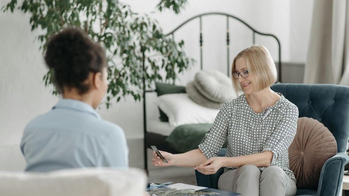 Two women engaging in a tarot card reading session in a peaceful indoor environment with soft furnishings.