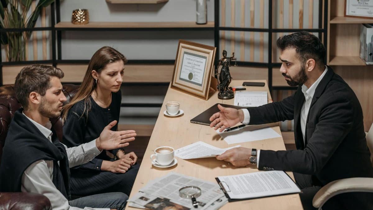 Lawyer consulting clients in an office. Documents and coffee on the table.