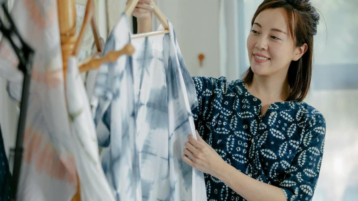 Asian fashion designer examining fabric material in her studio, smiling.