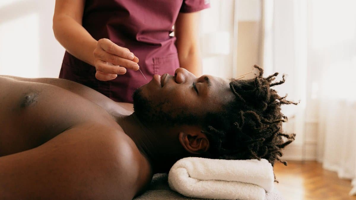 Acupuncture treatment on a relaxed man performed by a therapist in a serene setting.