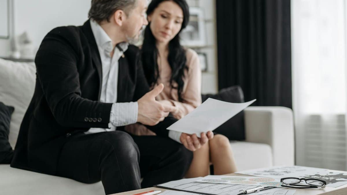 A couple discusses adoption paperwork in their living room, emphasizing their commitment and planning.