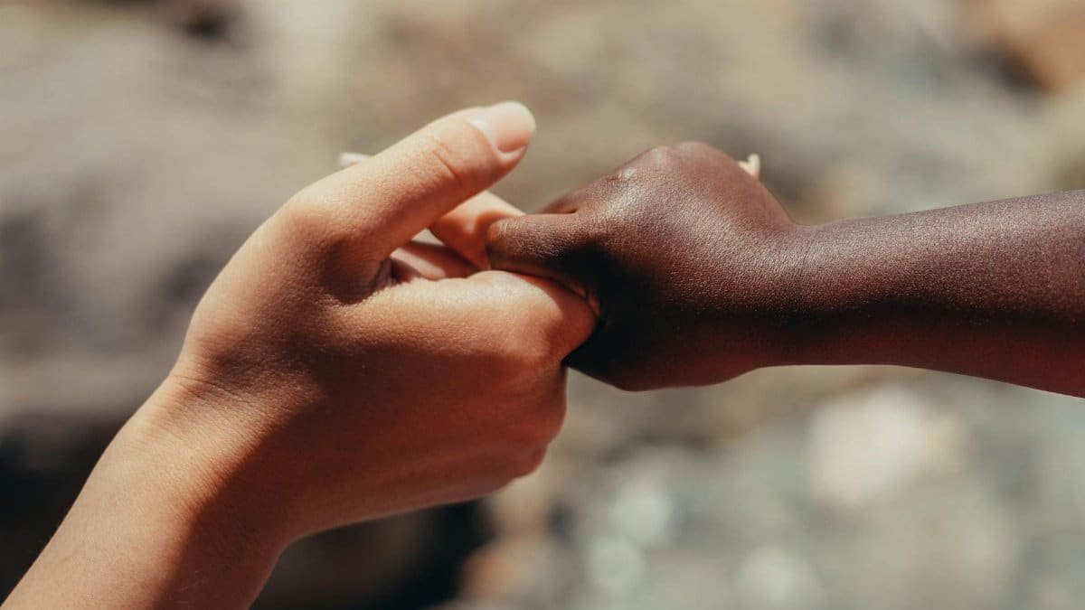 Close-up of two hands of different skin tones holding each other in support.