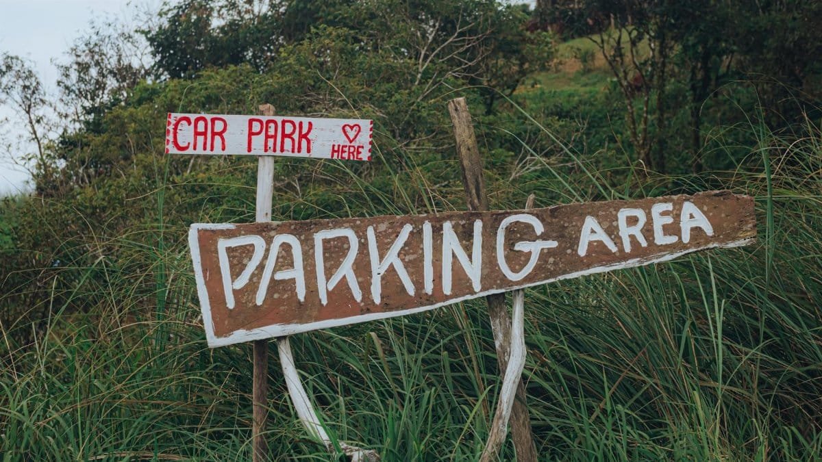 Handmade parking signs in a lush outdoor environment, guiding to car park.