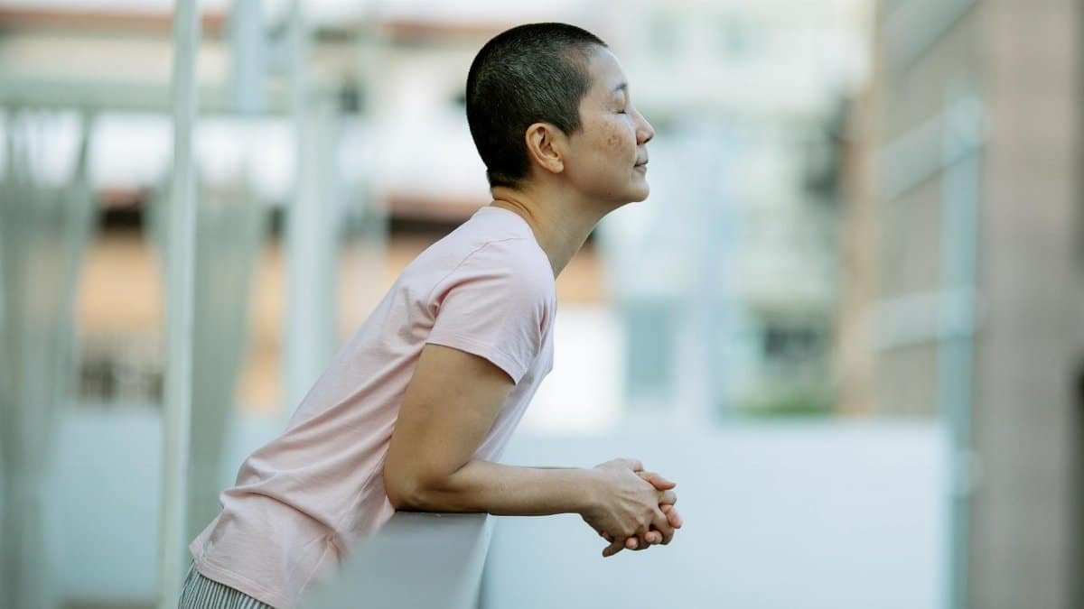 Side view of a calm woman with short hair relaxing on a balcony.
