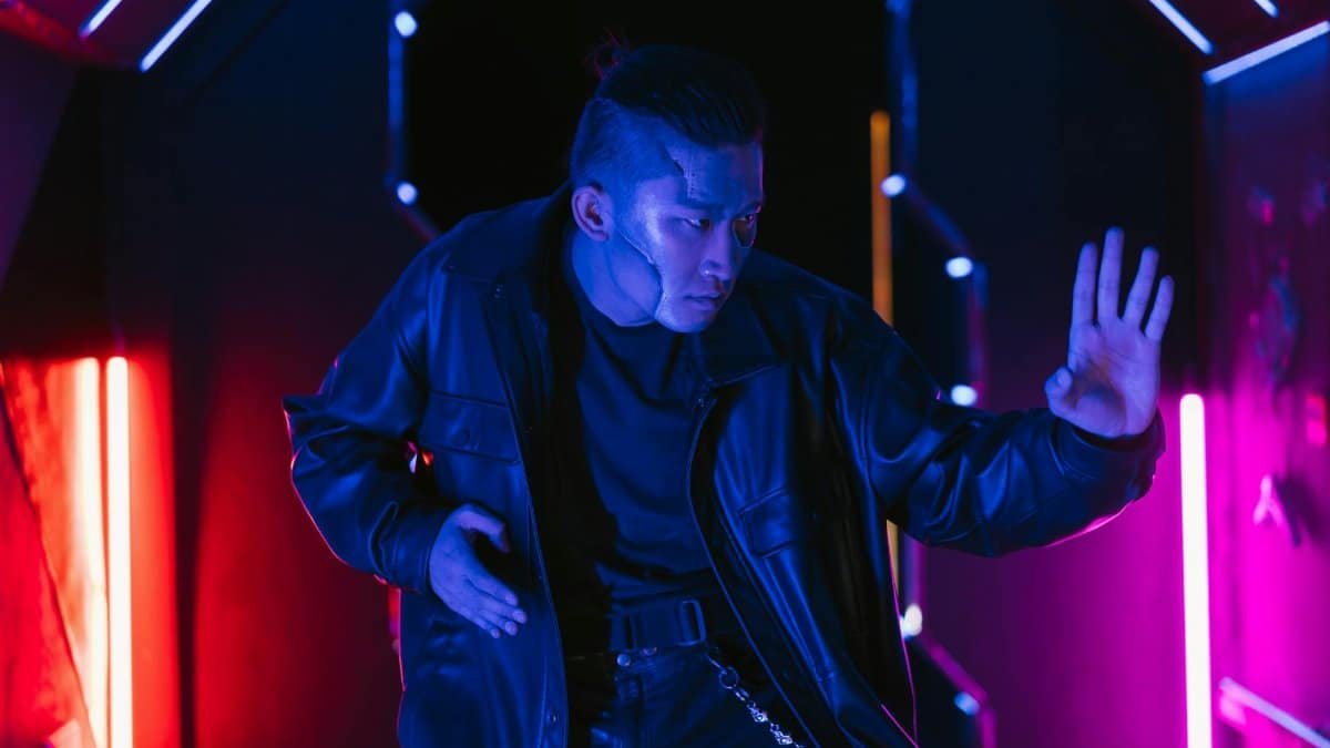 An Asian man in cyberpunk style poses against neon lights, conveying a futuristic vibe.