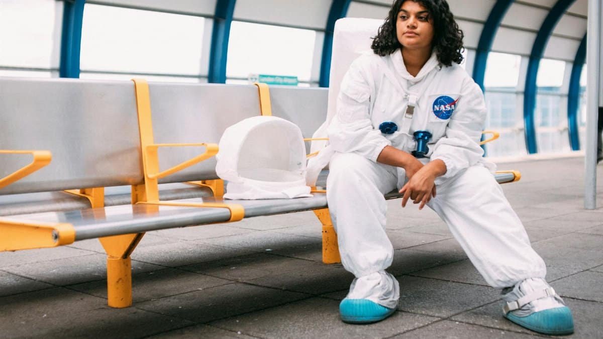 Woman in a NASA space suit sitting at a modern station, symbolizing exploration and future.