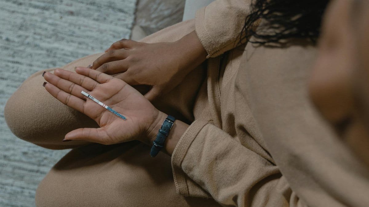 An adult with a pregnancy test in hand, conveying anticipation and hope.