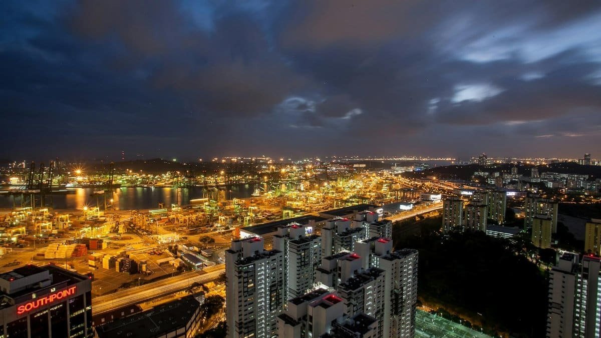 Stunning aerial view of a cityscape at night with skyscrapers and illuminated harbor.