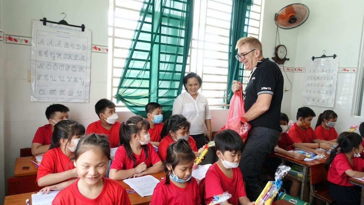 A teacher handing out gifts to students in a Vietnamese classroom.