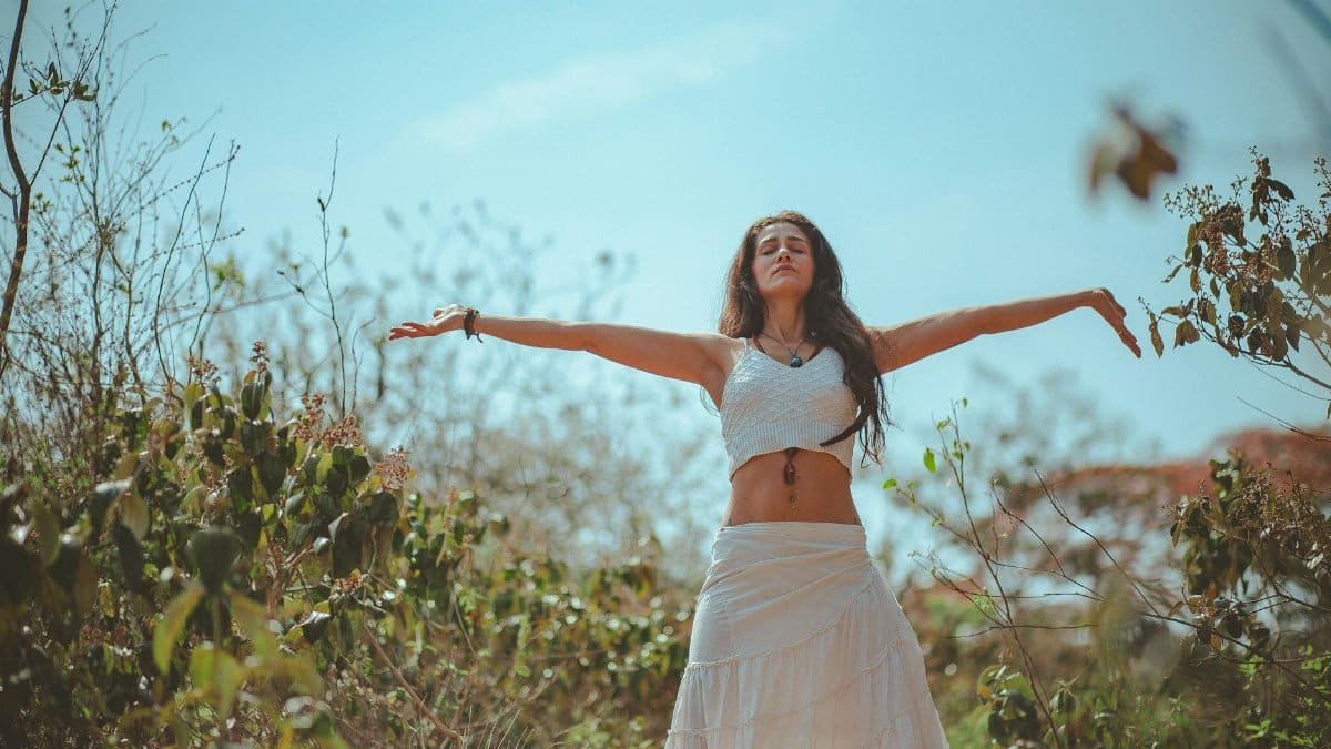 Peaceful scene of a woman meditating outdoors in a sunny summer setting, embodying wellness and tranquility.