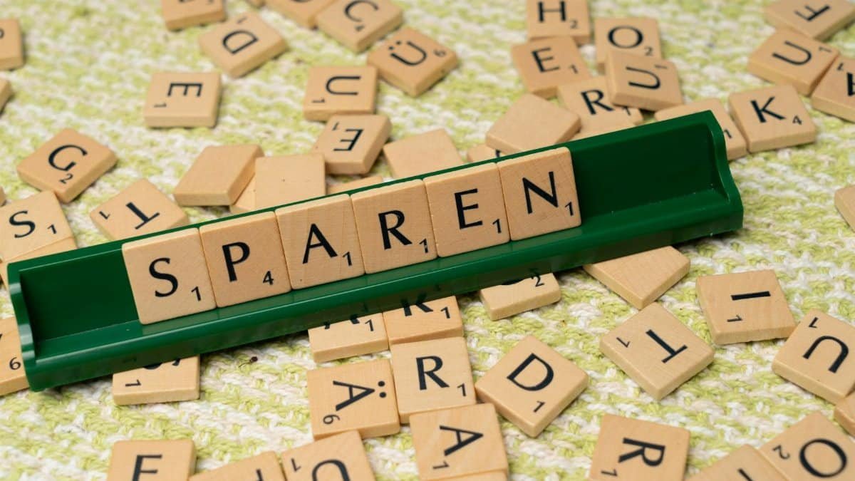 Close-up of Scrabble tiles spelling 'Sparen' on a green tile holder.
