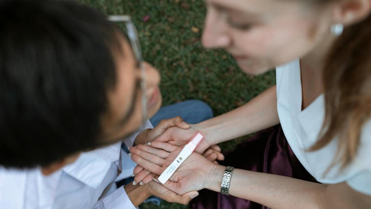 A happy couple joyfully reacts to a positive pregnancy test result in a serene outdoor setting.