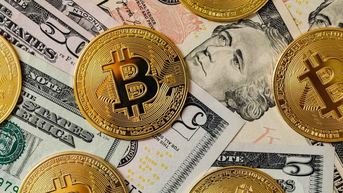 Golden bitcoins on a background of US dollar bills representing cryptocurrency and traditional money.