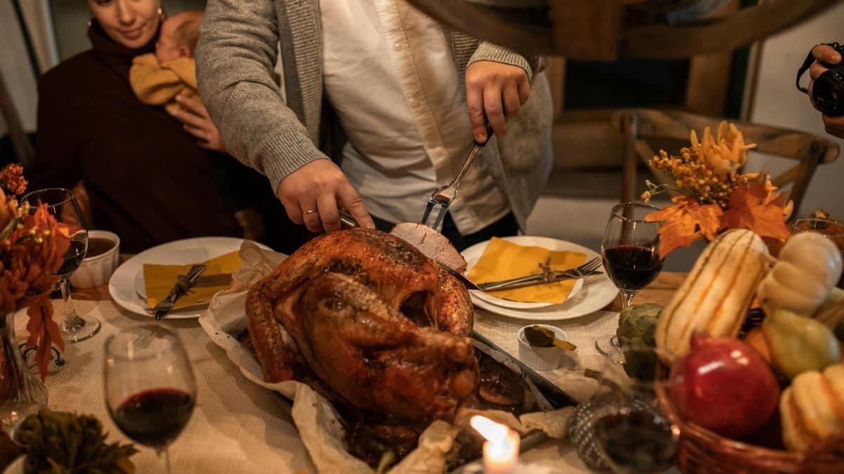 A festive Thanksgiving family gathering with carving a roasted turkey and holiday decor.