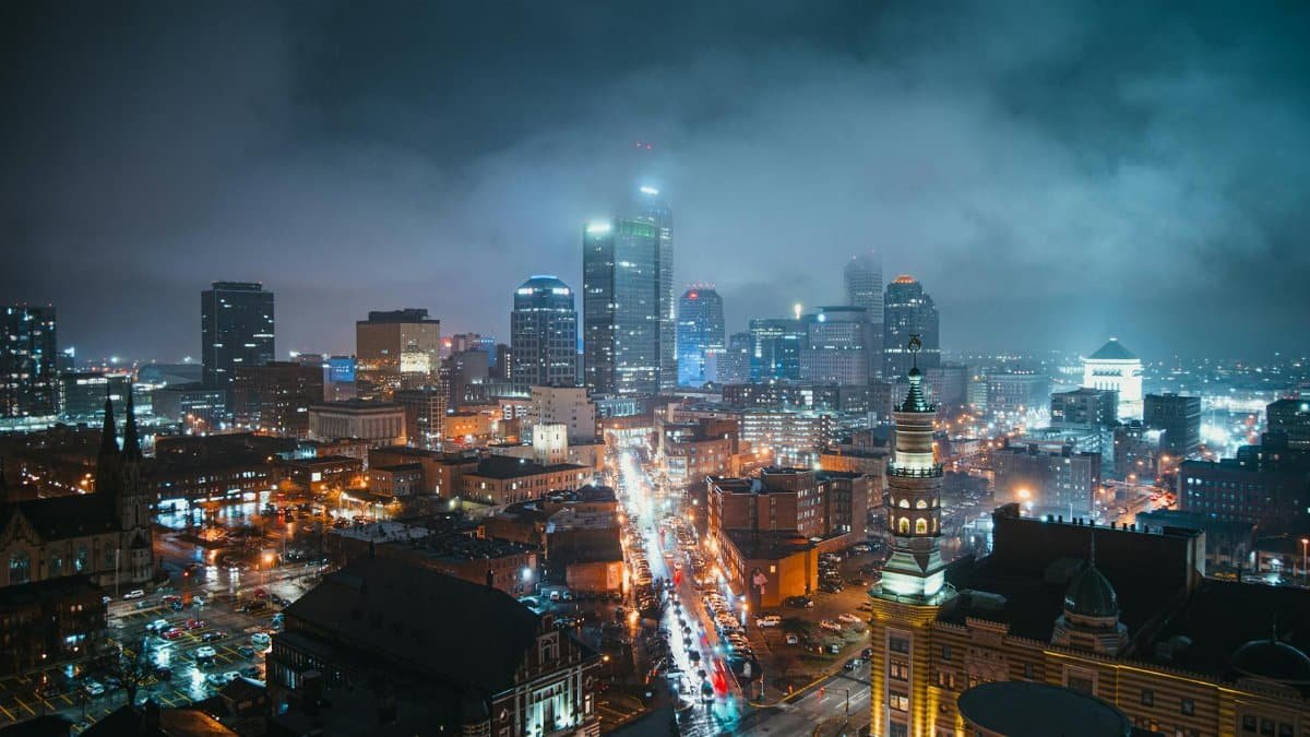 Stunning nighttime view of the Indianapolis skyline with illuminated skyscrapers and a bustling street below.