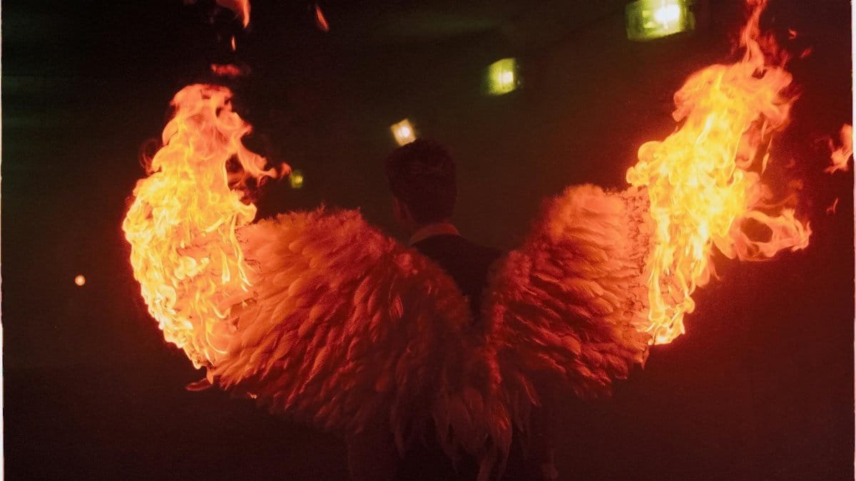 A dramatic image of angelic wings on fire, creating a striking visual in a dark setting.