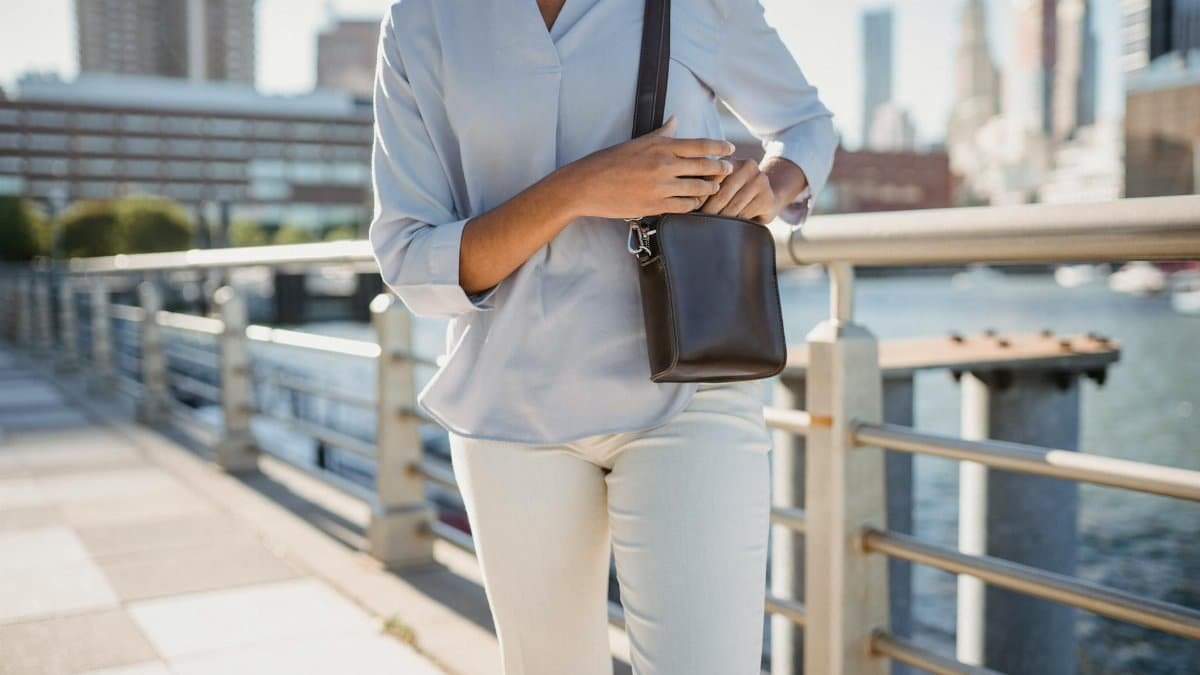 Fashionable woman in city setting with a stylish leather purse, enjoying a daytime walk.