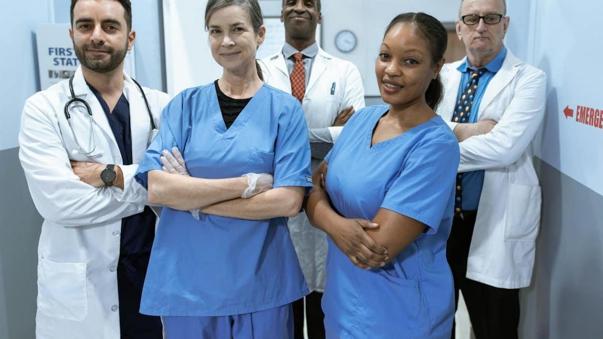 A diverse team of doctors and nurses smiling confidently in a hospital setting.
