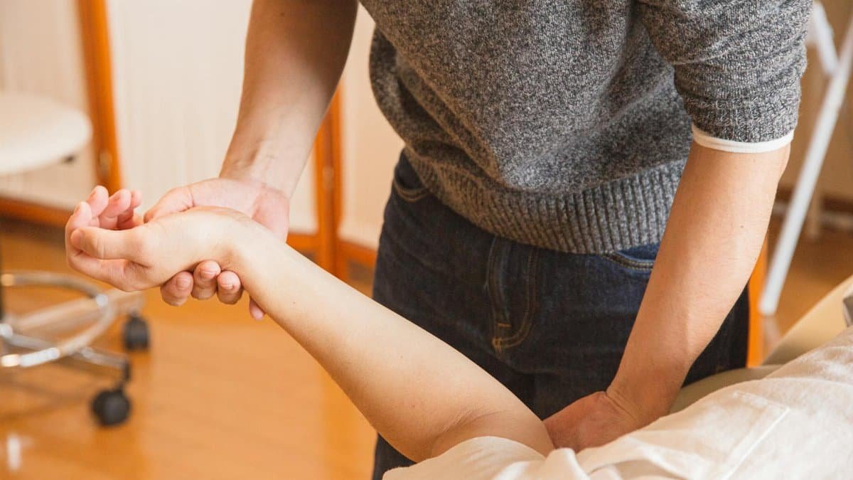 Therapist assisting a patient with wrist therapy. Focus on healthcare and wellness.