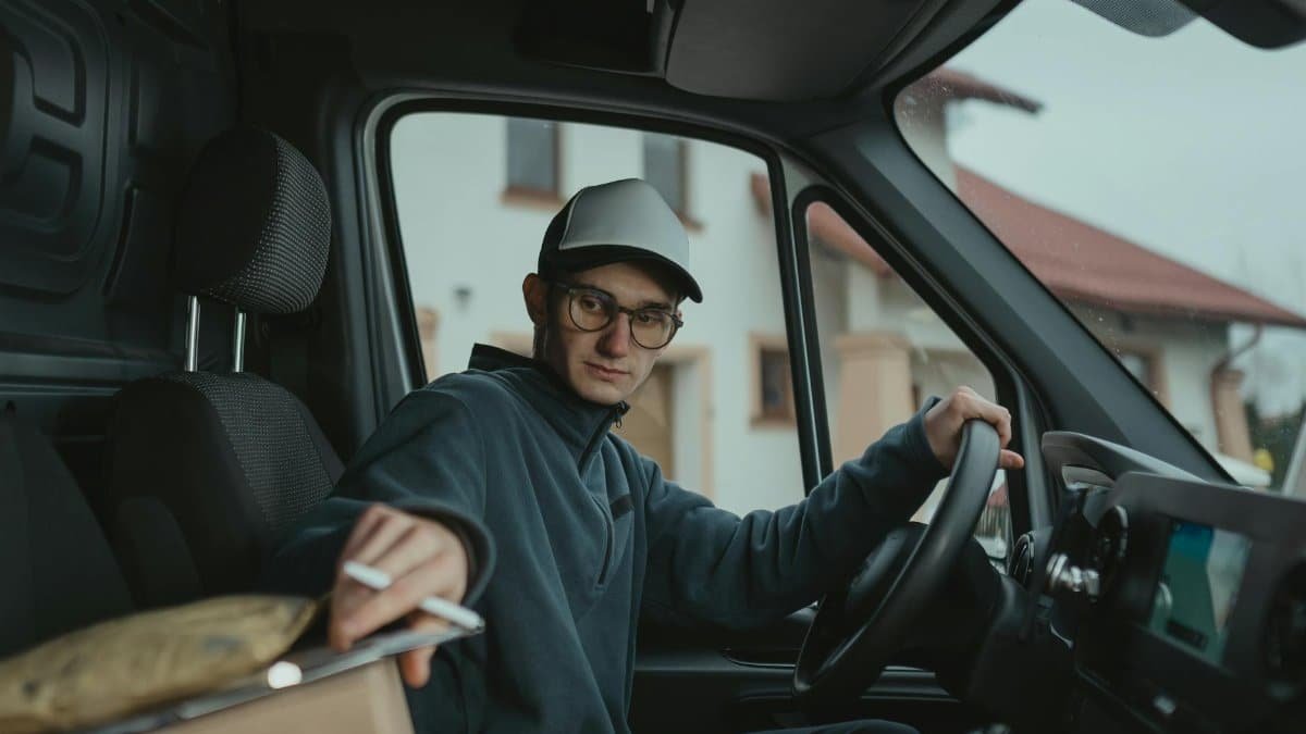 Young delivery driver inside a van preparing to deliver a package, showcasing logistics work.