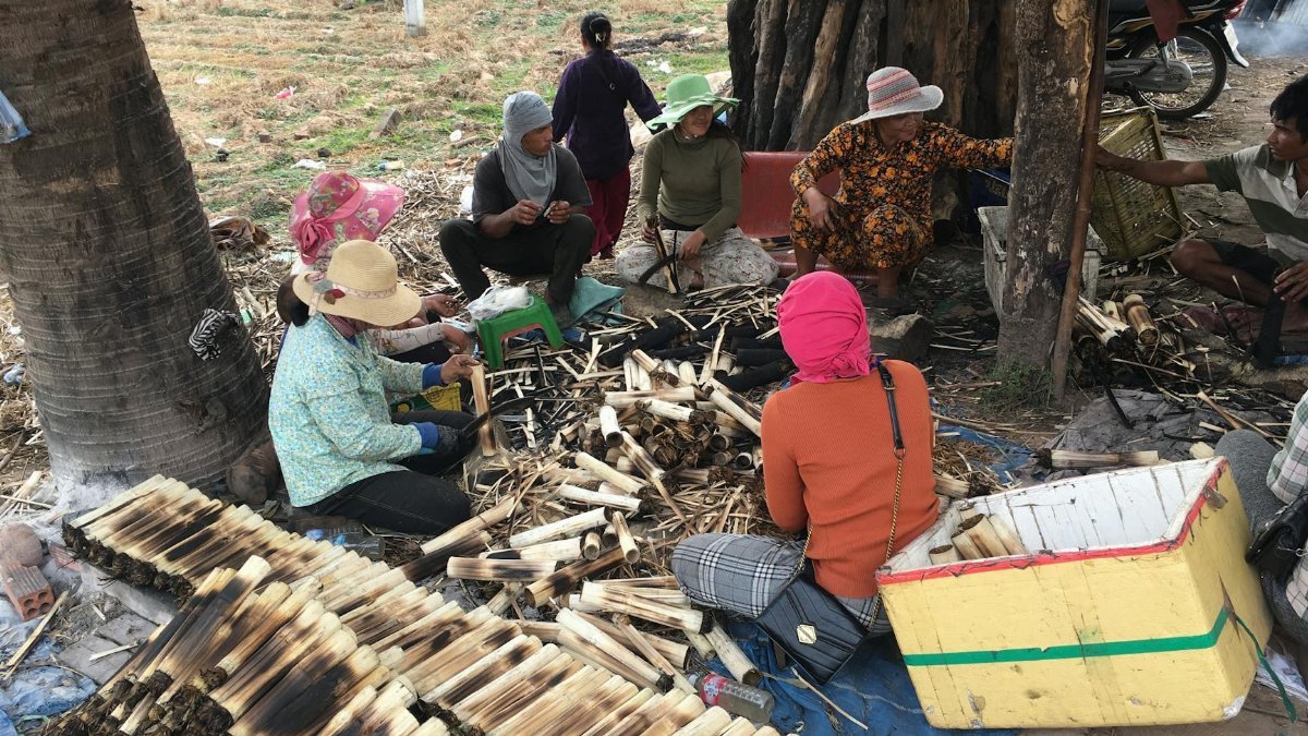 Group of people crafting bamboo products outdoors, showcasing local culture and community effort.