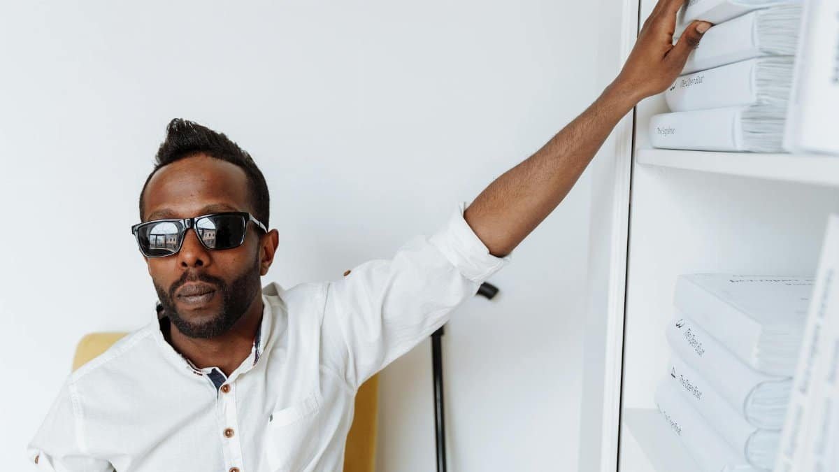 African American man with visual impairment selecting books in a modern library.