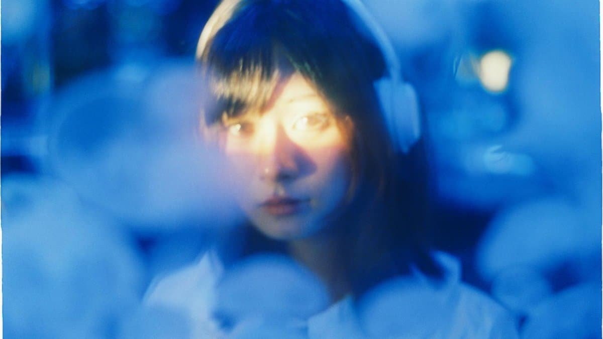 A woman listening to music with headphones is captured in a dreamy, blue-tinted light.